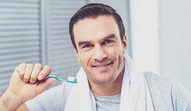 Mann mit erneuerten Zähnen und Zahnbürste